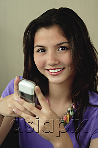 AsiaPix - A teenage girl smiles at the camera as she uses her cellphone