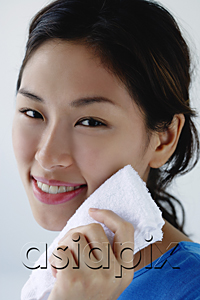 AsiaPix - A young woman smiles at the camera as she washes her face