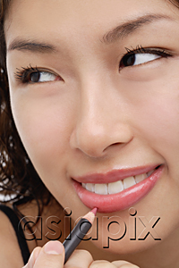 AsiaPix - A young woman applies lip pencil