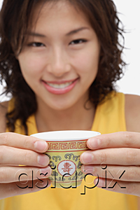 AsiaPix - A woman looks at the camera as she holds out a cup of tea