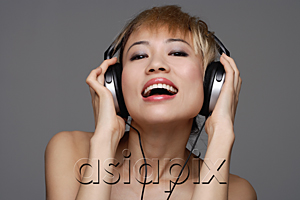 AsiaPix - A young woman with headphones on listens to music as she looks at the camera