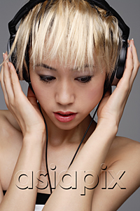 AsiaPix - A young woman with headphones on listens to music