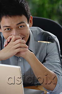 AsiaPix - A man smiles at the camera as he sits at his desk