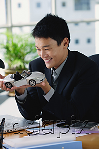 AsiaPix - A man plays with a toy car on his desk