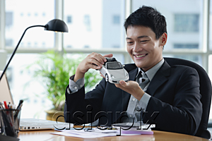AsiaPix - A man plays with a toy car on his desk