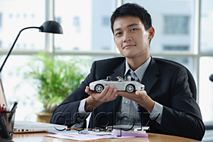 AsiaPix - A man looks at the camera as he holds a toy car