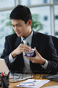 AsiaPix - A man sits at his desk as he holds a Chinese tea cup
