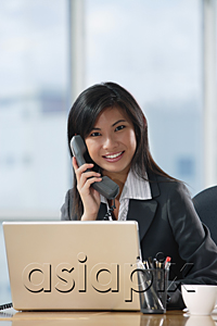 AsiaPix - A woman looks at the camera and talks on the phone as she sits at her desk