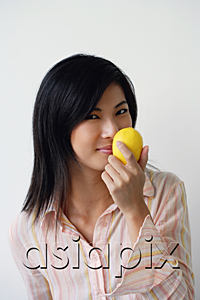 AsiaPix - A woman looks at the camera as she holds up a lemon