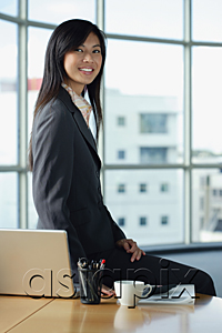AsiaPix - A woman smiles at the camera as she sits on her desk