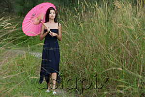 AsiaPix - Woman walking in long grass with parasol