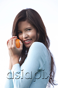 AsiaPix - Woman holding orange, looking at camera