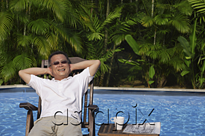 AsiaPix - Man relaxing in deck chair by the pool