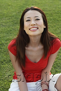 AsiaPix - Woman sitting in park, smiling at camera