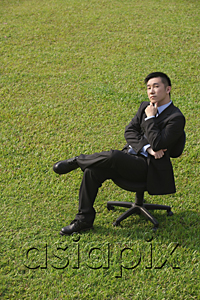 AsiaPix - Businessman with quizzical expression sitting on office chair