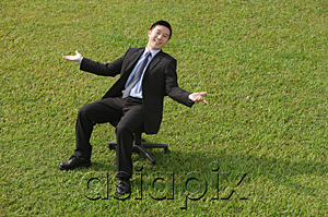 AsiaPix - Businessman sitting on an office chair, smiling at camera