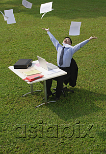 AsiaPix - Businessman sitting at desk and throwing paper in the air