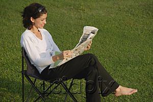 AsiaPix - Woman reading newspaper in the park