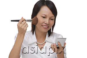 AsiaPix - Woman applying make-up  while looking into compact mirror