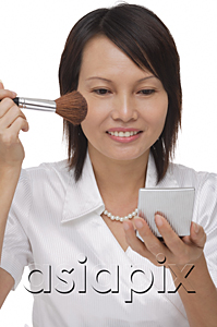 AsiaPix - Woman applying cosmetics while looking into compact mirror