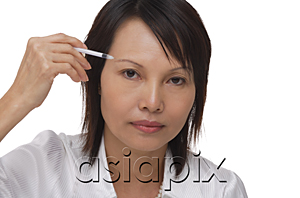 AsiaPix - Woman applying make-up while looking at camera