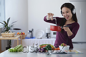AsiaPix - Young woman cooking while listening to music