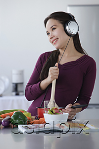 AsiaPix - Young woman cooking while listening to music