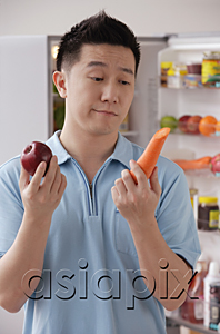 AsiaPix - Man holding an apple and a carrot, looking frustrated