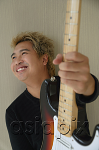 AsiaPix - Man with guitar smiling and looking into distance