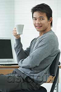 AsiaPix - Man with cup relaxing at desk and looking at camera
