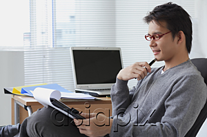 AsiaPix - Man in office chair writing on clipboard
