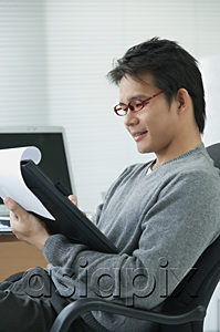 AsiaPix - Man in office chair writing on clipboard