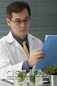 AsiaPix - Scientist examining jar with plant samples