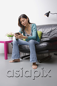 AsiaPix - Young woman sitting on couch using organizer