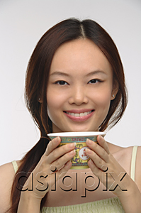 AsiaPix - Young woman with traditional tea cup smiling at camera