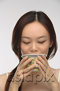 AsiaPix - Young woman drinking tea from traditional tea cup
