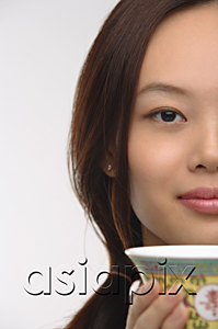 AsiaPix - Young woman with traditional tea cup looking at camera