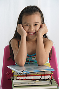 AsiaPix - Young girl with books on lap smiling at camera