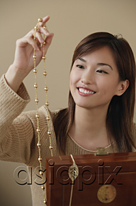 AsiaPix - Young woman smiling at necklace