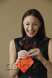 AsiaPix - Young woman laughing while opening red envelope