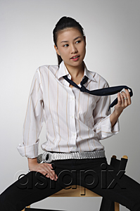 AsiaPix - Young woman sitting and playing with tie