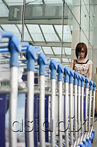 AsiaPix - Young woman retrieving trolley at the airport
