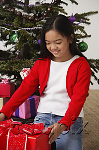 AsiaPix - Girl looking at Christmas presents with smile