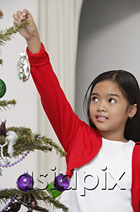 AsiaPix - Girl hanging up Christmas decoration to the tree