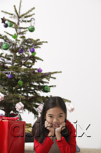 AsiaPix - Girl elbow on ground with Christmas present and Christmas tree at the background