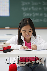 AsiaPix - Girl writing and sitting at school desk