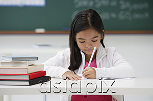 AsiaPix - Girl writing and sitting at school desk