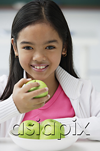 AsiaPix - Girl holding green apple in one hand smiling at camera