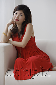 AsiaPix - Young woman sitting on sofa smiling at camera
