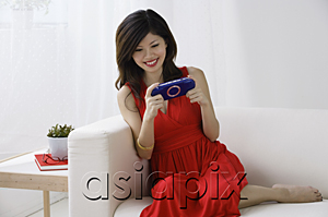 AsiaPix - Young woman playing with handheld video console